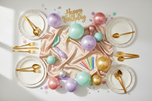 Colorful party supplies including balloons, candles, and tableware arranged for a birthday celebration