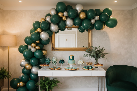 Lush DIY balloon garland in teal, green, and gold draped over a party dessert table