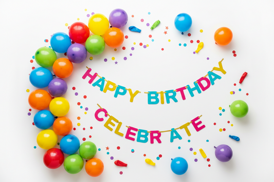 Colorful party decorations flat lay featuring rainbow latex balloons, balloon garland, confetti, and festive banners for birthday and wedding celebrations
