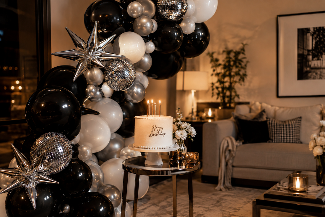 Black, silver, and white balloon garland with disco-style foil accents beside a cake at an adult birthday party.